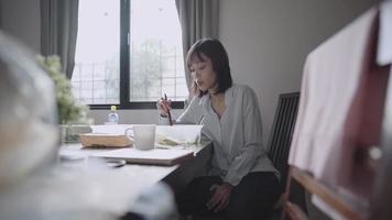 mujer trabajadora asiática comiendo en casa, servicio de entrega de alimentos, usando palillos y cuchara, servicio de entrega de alimentos para llevar comida, mujer soltera que se queda sola, vida económica, mantener la distancia, luz de la ventana video