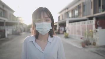 confidence Asian woman wear protective medical face mask, Coronavirus covid19 protection, outdoor sunset shot, walking around the neighborhood, life insurance, keep distance, public risk prevention video