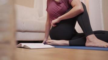 fitness sportivo multitasking donna asiatica che fa yoga e legge a casa soggiorno durante la quarantena covid-19, allenamento a casa esercizio in soggiorno, esercizio di yoga a casa, benessere calmo relax video