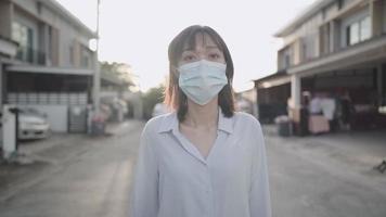 mujer asiática usa mascarilla protectora, se siente segura de salir del vecindario de la casa, nuevo estilo de vida normal covid-19 pandemia, protección de enfermedades infecciosas, prevención de riesgos, problema de contaminación del aire video