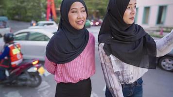 primo piano due stand asiatici sul lato della strada trafficata della città indicano la strada, un turista amico femminile si perde per le visite turistiche della città, le persone e la religione, belle studentesse arabe in hijab in strada. Islam video