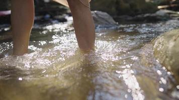 Close up of slim legs walking through a fast flowing stream, smooth legs slowly strolling across the waterfall river, living with nature, stay out of chaos from city, relaxing exercising video