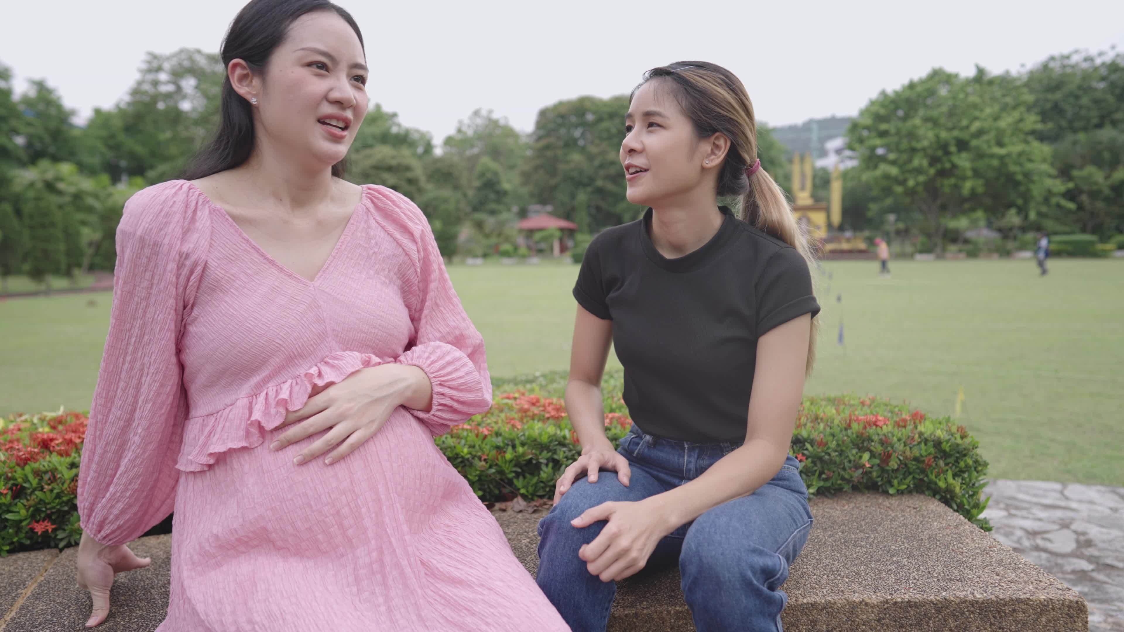 Asian females friends discuss about feminine topic, expectant mother support, women society, upcoming new born baby, girlfriends having a conversation at outdoor park, proud mom showing off her baby