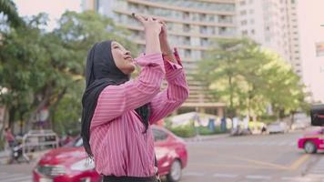 Young Asian Muslim female wear hijab taking photo of the beautiful city skyscape architect on her travel trip, modern Muslim lifestyle and travel, sharing photos online, enjoying holiday vacation, video