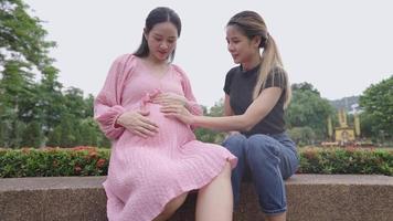 dos amigas jóvenes comparten experiencias de estar embarazadas, una amiga rubia emocionada toca suavemente a la futura madre y observa mientras el bebé se mueve en la etapa de embarazo, confía y alienta