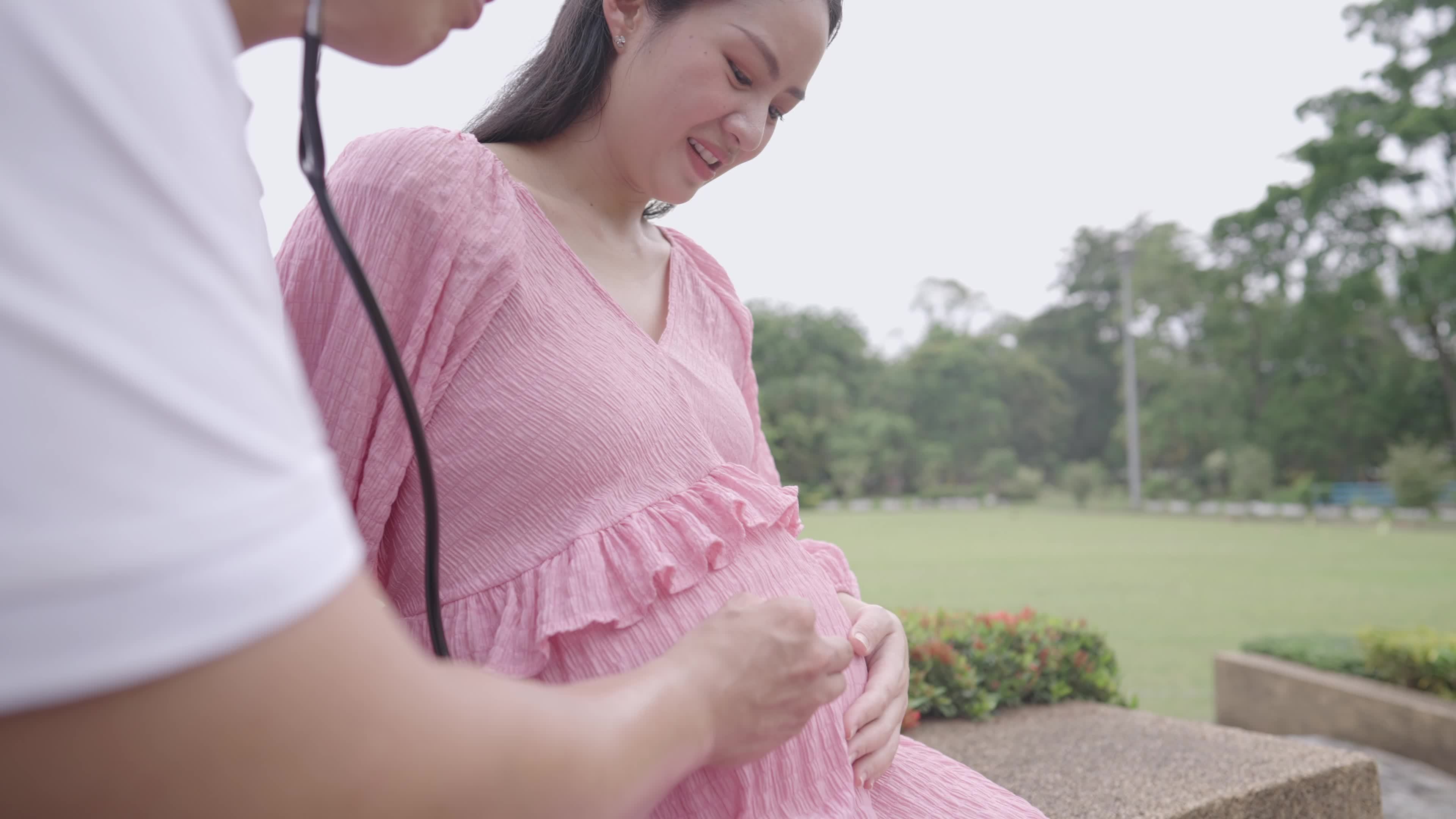 Closeup in beautiful moment of young parent using stethoscope listen to unborn baby inside