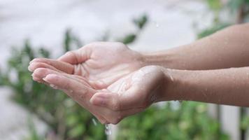 close up two hands wait to catch Rain drops, rainy day. touch the nature, rains water Palm, rainy season slow motion, suitability living concept, save and  preserve water energy and natural recourses,