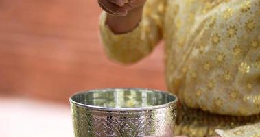 close-up, tiro em câmera lenta, mão feminina coloque flores de jasmim na água na tigela, prepare a fragrância da água antes de derramá-la para fazer um desejo dos idosos no festival songkran