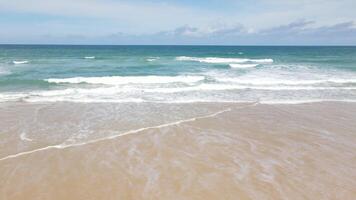 vista aérea da praia de areia e textura da superfície da água. ondas espumosas com céu. drone voando da bela praia tropical. incrível litoral arenoso com ondas do mar branco. conceito de natureza, marinha e verão. video