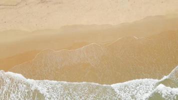 vista aérea da praia de areia e textura da superfície da água. ondas espumosas com céu. drone voando da bela praia tropical. incrível litoral arenoso com ondas do mar branco. conceito de natureza, marinha e verão. video