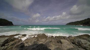 havsvågor slår mot klipporna vid kusten och skapar en explosion av vatten. skummande vågor med himmel. vacker tropisk strand. fantastisk sandstrand med vita havsvågor. natur, havsbild och sommar. video