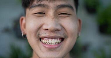 Close up face of Happy Asian male gardener owner smiling and looking at camera in the garden. Home greenery, selling online and hobby concept. video