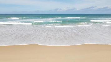 vue aérienne de la plage de sable et de la texture de la surface de l'eau. vagues mousseuses avec ciel. belle plage tropicale. incroyable littoral sablonneux avec des vagues de mer blanche. nature, paysage marin et concept d'été.