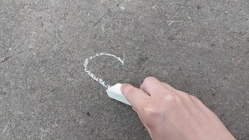 ragazza disegna un cuore con il gesso sulla lavagna. amore, romanticismo. disegno, creatività video