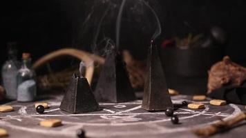 schwarze Zauberkerzen brennen. Rauch auf dem Hintergrund der magischen Attribute der schwarzen Kunst. Halloween-Konzept. video