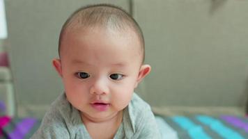 lycklig familj, söt asiatisk nyfödd pojke som spelar på sängen och tittar på kameran med ett leende ansikte. lite oskyldigt nytt spädbarn bedårande barn i första dagen i livet. mors dag koncept. video