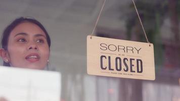 Small business entrepreneur, Beautiful Asian woman owner or Manager restaurant, Waitress. Walking up to door or window for changing closed to open sign with smile looking outside waiting for clients. video