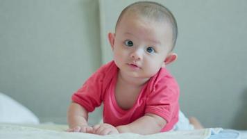 gelukkige familie, schattige aziatische pasgeboren baby draag rood shirt liggend spelen op wit bed met lachende glimlach blij gezicht. kleine onschuldige nieuwe baby schattig kind in de eerste dag van het leven. moederdagconcept.