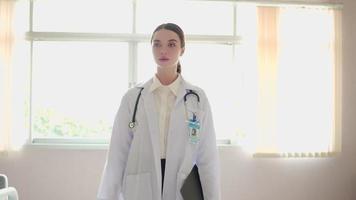 Portrait of Confident successful young female physician smile. Doctor walk working in examination room hospital medical office. Expertise, professional doctor in uniform white lab coat, stethoscope. video
