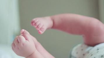 schuss der hand des niedlichen neugeborenen babys, das die hand erreicht oder spielt und die füße berührt, genießen sie, während sie auf dem bett liegen. glückliche familie, kleines unschuldiges neugeborenes entzückendes am ersten lebenstag. Muttertagskonzept. video