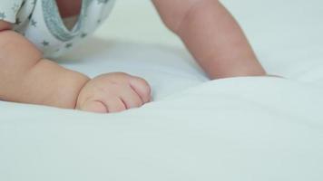 close-up kleine hand van schattige baby pasgeboren handbereik kruipen of spelen liggend op wit bed. gelukkig gezin, kleine onschuldige nieuwe baby, schattig nieuw leven en ouderschap. kindertijd concept. video