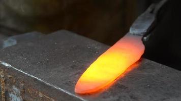 Man hitting a red metal. Making a blade of a knife in Black smith video
