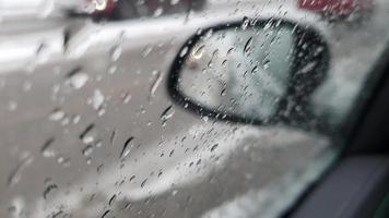 dia chuvoso em um carro. gotas de chuva caindo na janela de um carro e outros carros passando