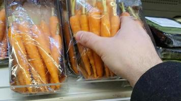 Man taking carrot in supermarket. Healthy food concept video