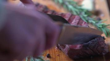 De délicieux steaks chauds coupés sur une planche à découper en bois avec un couteau video