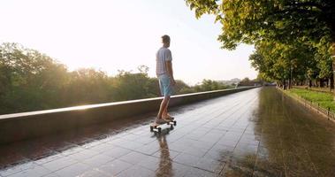 bel giovane maschio con skateboard all'aperto in città ascolta musica con le cuffie video