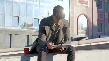 macho joven lee un libro al aire libre en la calle video