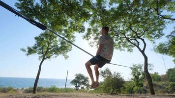 Athlete walking in slackline in the park with sea and blue sky on background video