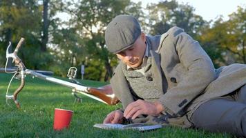 Young male hipster with retro bicycle read book in autumn park video