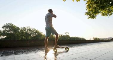 hübscher junger Mann mit Skateboard im Freien in der Stadt Musik mit Kopfhörern hören video