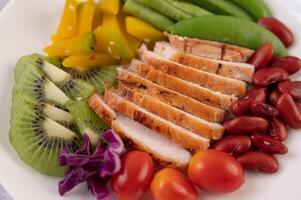 Chicken steak with peas, tomatoes, kiwi and pumpkin. photo