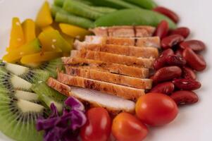 Chicken steak with peas, tomatoes, kiwi and pumpkin. photo