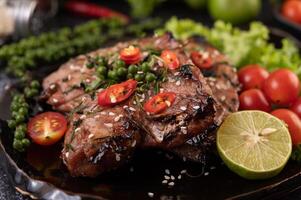 Pork steak topped with white sesame and fresh pepper seeds along. photo