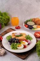 el desayuno consiste en pan, huevos cocidos, aderezo para ensalada de uva negra, tomates.