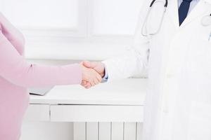 female hand of the doctor shakes the female arm of his patient in clinic, medical office. Healthcare concept, health insurance photo