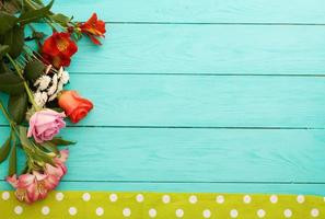 Frame of flowers and towels in polka dots on blue wooden background. Top view and selective focus. Copy space photo