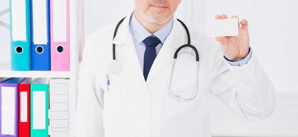 Doctor showing business card in clinic, medical insurance, man in white uniform. Copy space photo