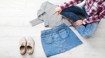 ropa casual de verano con diferentes accesorios y piernas femeninas en jeans sobre suelo de madera blanca. vista superior y espacio de copia. foto