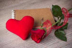 Red rose and note book on old wood background photo