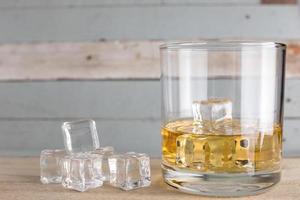 whiskey glasses with ice cubes isolated on old wood photo