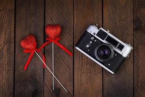 Vintage old camera with hearts on rustic wooden background. Top view photo