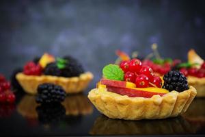 Tartlets with different berries on dark background photo