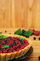 Delicious tart with custard and currant on wooden background photo