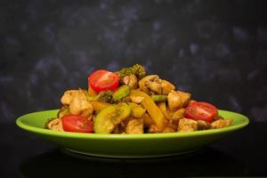 Stir fry chicken, zucchini and broccoli on dark background photo