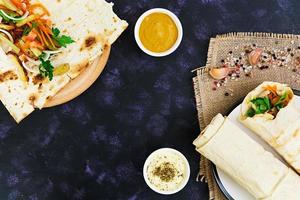 Shawarma sandwich with ingredients on dark background. Top view photo