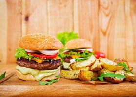 Delicious handmade burger on wooden background. Close view photo